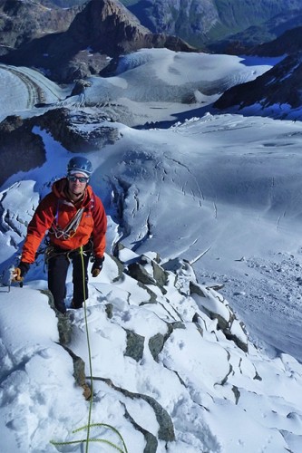 Hochtourengeher mit Hochtourenausrüstung steht an einem Berghang hinauf zum Gipfel des Piz Palü.