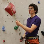 Kletterer sichert in der Kletterhalle mit einem Clip Up als Sicherungsbrille.