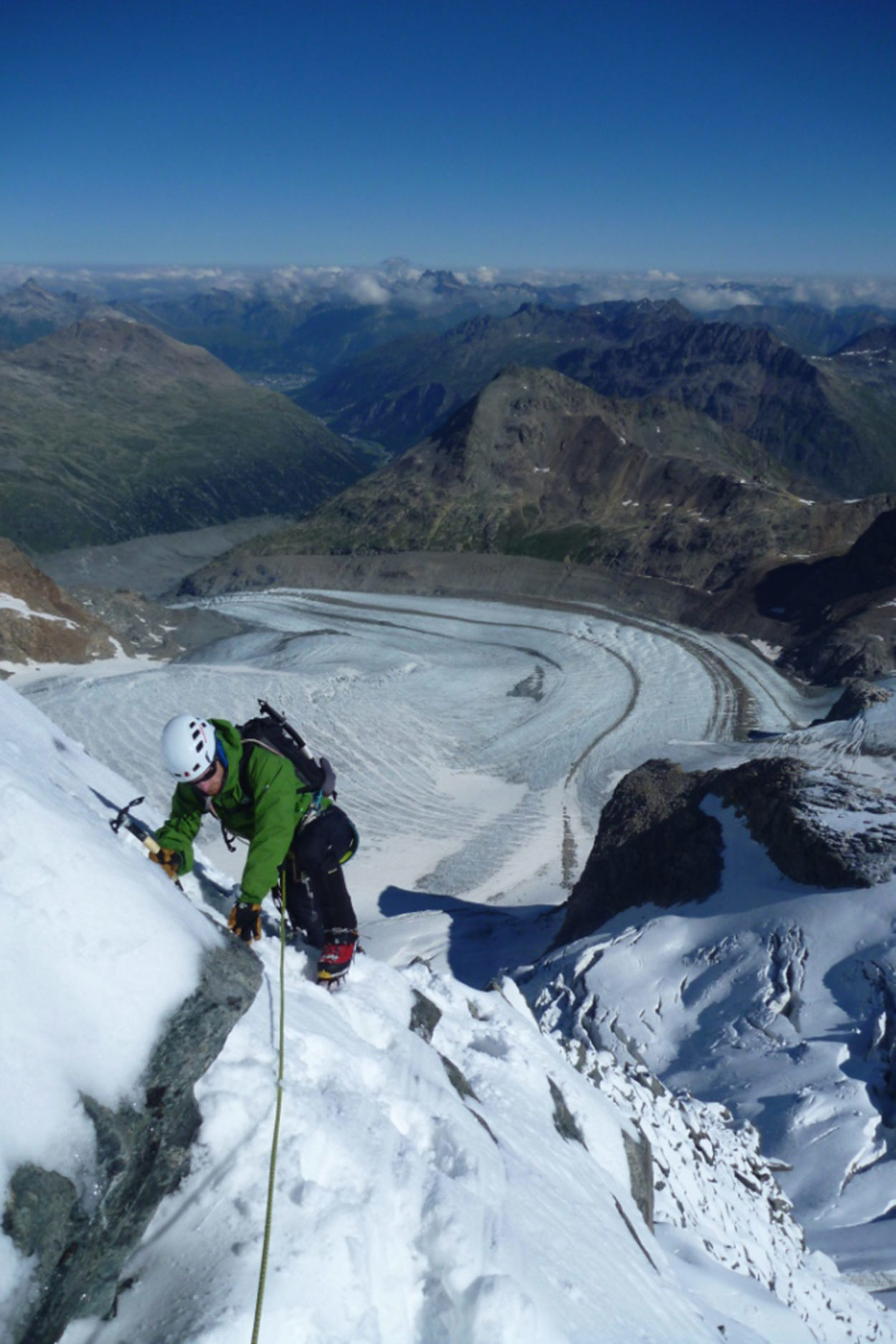 Hochtourengeher steigt mit Pickel und Steigeisen den schneebedeckten Berg Piz Palü hinauf.