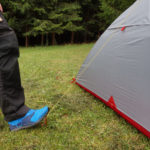 Mann drückt mit Fuß auf Zelthering