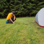 Man befestigt Zelt mit Sturmleinen