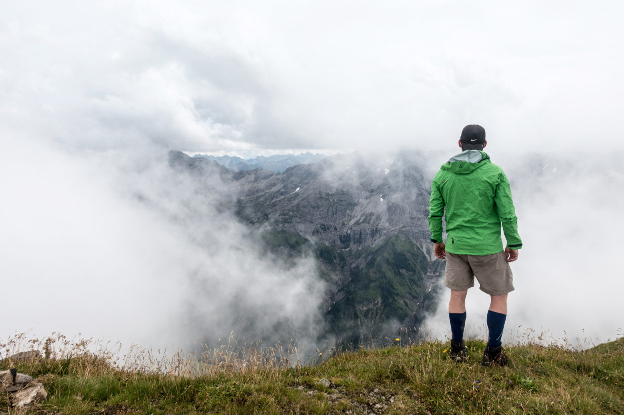 Wanderer steht mit Calgary Jacke von Schöffel vor nebeligem Berg.