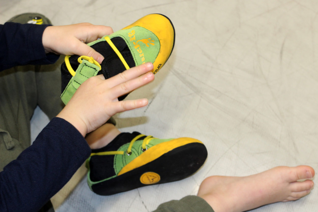 Ein Kind zieht Kinderkletterschuhe an