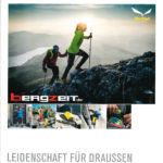 Zwei Trailrunner/Wanderer mit Stöcken laufen auf felsigem Untergrund einen Berg hinauf in der Dämmerung