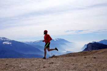 Trailrunner läuft vor Bergpanorama und See