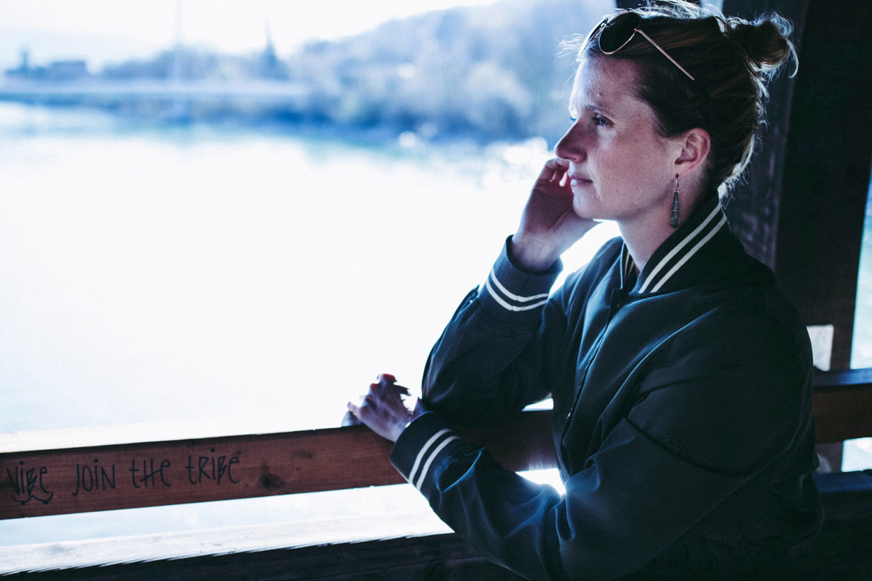 Frau lehnt an Brückenbrüstung in olivgrünem LangerChen Mantel