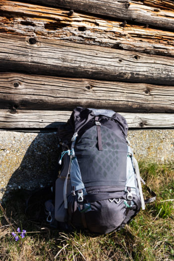 Gregorgy Maven 55 Wanderrucksack lehnt an Hüttenwand in der Sonne