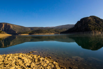 Spiegelglatter Fluss mit bewaldeten Hügeln im HIntergrund