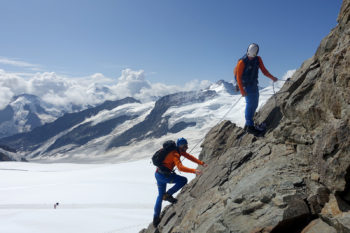Zwei Bergsteiger klettern eine einfache Felswand rauf.