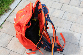 Ein oranger Rucksack mit weit geöffnetem Hauptfach.