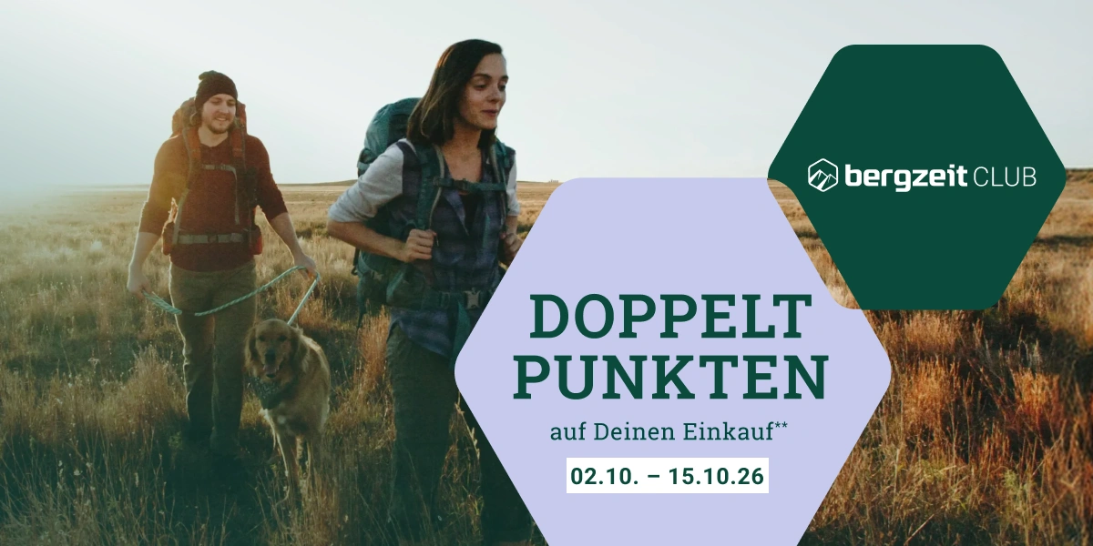 Zwei Personen wandern über herbstliche Wiese, im Vordergrund eine lila sechseckige Fläche mit Text "Doppelt punkten auf deinen Einkauf** 02.10.-15.10.“ und eine dunkelgrüne sechseckige Fläche mit weißem Bergzeit Club Logo